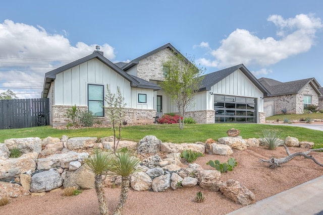 modern farmhouse with an attached garage, board and batten siding, fence, and a front yard