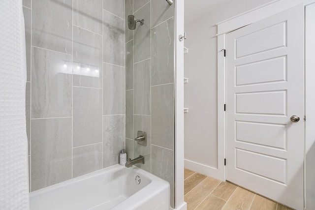 bathroom featuring baseboards, shower / bathtub combination with curtain, and wood finished floors
