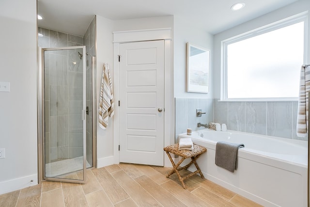 full bathroom with recessed lighting, wood finished floors, a bath, and a stall shower