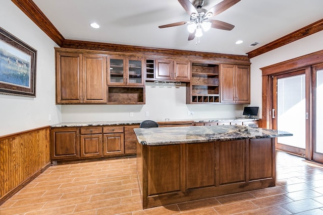 kitchen featuring stone counters, crown molding, wooden walls, and ceiling fan