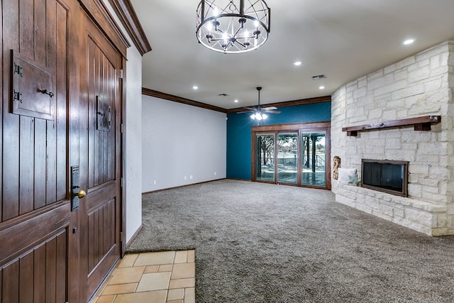 unfurnished living room with crown molding, light colored carpet, a stone fireplace, and ceiling fan with notable chandelier