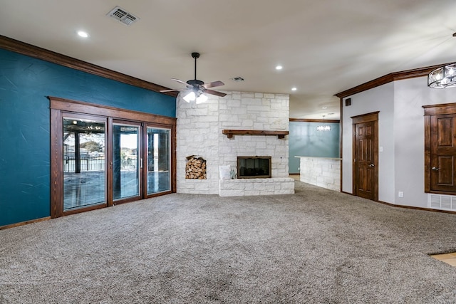 unfurnished living room with crown molding, ceiling fan, a stone fireplace, and carpet