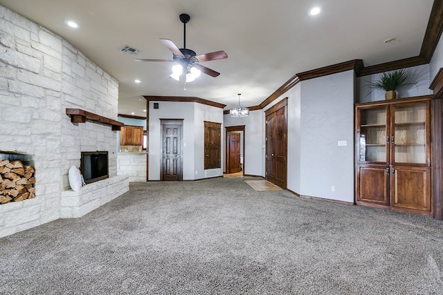 unfurnished living room featuring crown molding, a fireplace, ceiling fan with notable chandelier, and carpet flooring