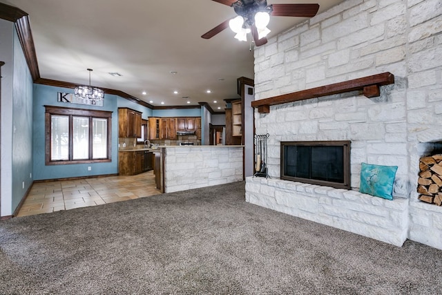 unfurnished living room with sink, crown molding, ceiling fan, a fireplace, and light colored carpet