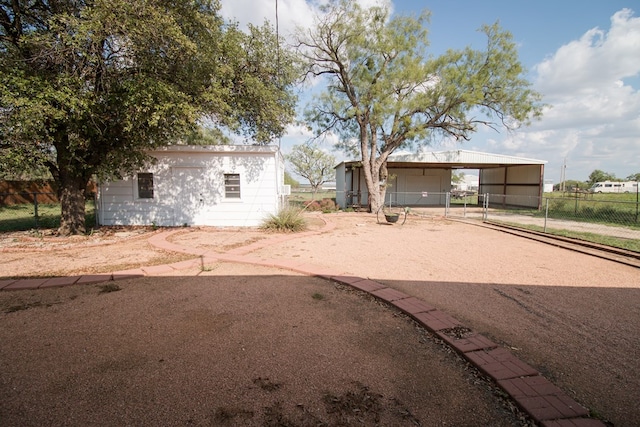 view of front of home with a detached carport, fence, and an outbuilding