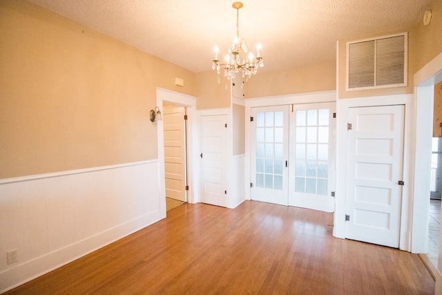 interior space with visible vents, a wainscoted wall, a notable chandelier, and wood finished floors