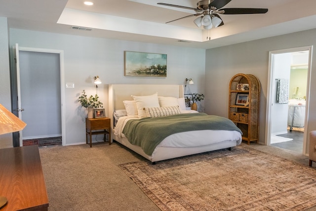 carpeted bedroom featuring a raised ceiling and ceiling fan