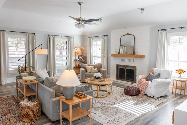 living room with a wealth of natural light, a brick fireplace, hardwood / wood-style floors, and ceiling fan