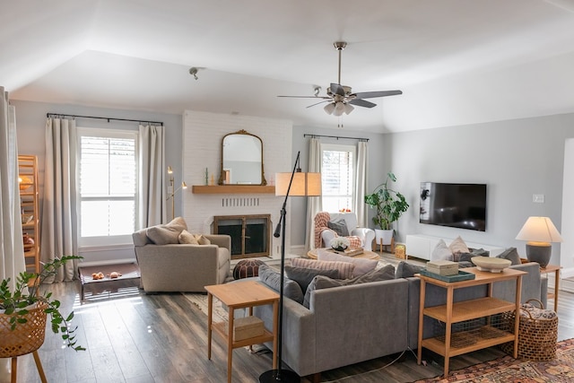 living room with dark wood-type flooring, ceiling fan, plenty of natural light, and a brick fireplace