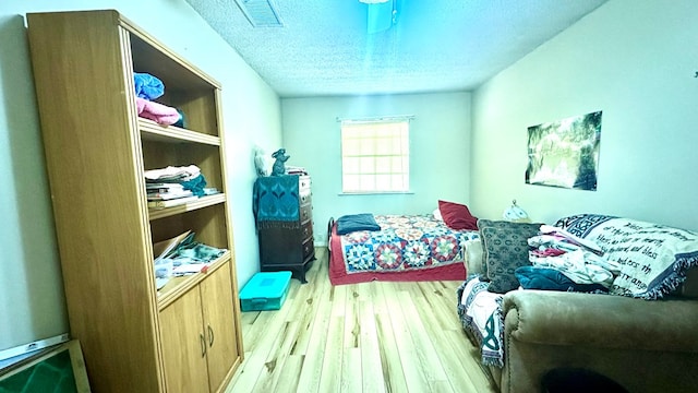 bedroom featuring visible vents, a textured ceiling, and light wood finished floors