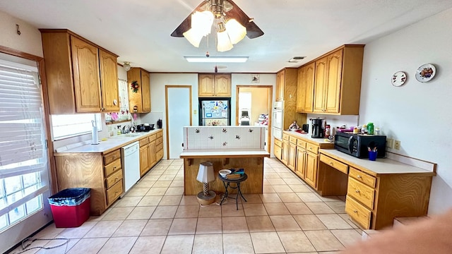 kitchen with a kitchen island, black microwave, light countertops, and dishwasher