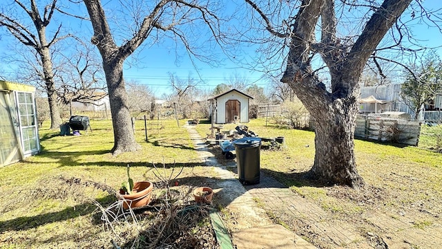 view of yard with a shed, fence, and an outbuilding