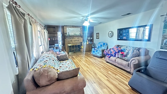 living area featuring plenty of natural light, a fireplace, visible vents, and wood finished floors