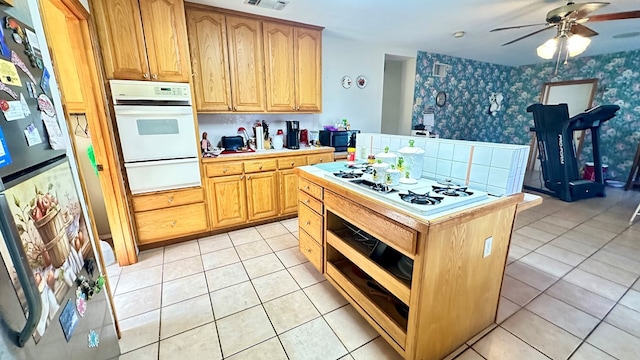 kitchen featuring a warming drawer, light tile patterned floors, light countertops, white appliances, and wallpapered walls