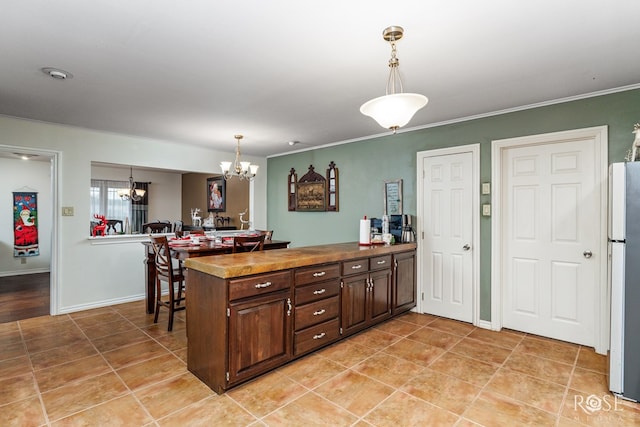 kitchen featuring white refrigerator, dark brown cabinets, kitchen peninsula, and decorative light fixtures