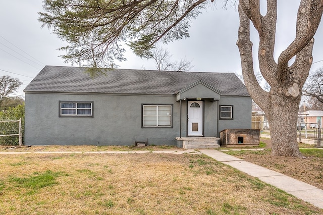 512 Ave J, Ozona, TX 76943 - view of front facade with stucco siding, a shingled roof, a front yard, and fence