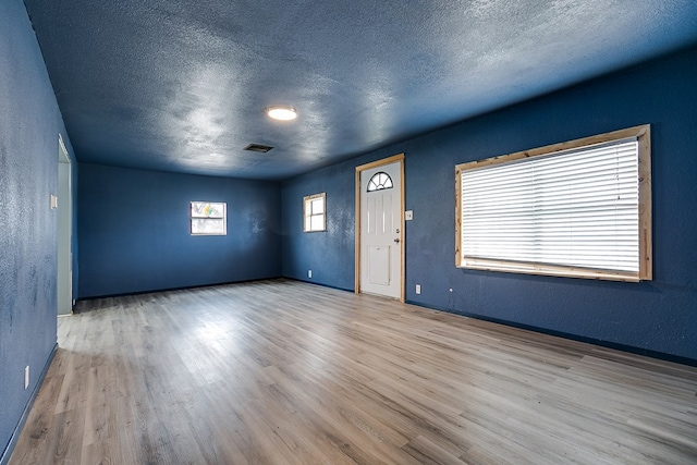 512 Ave J, Ozona, TX 76943 - spare room featuring visible vents, a textured ceiling, wood finished floors, and a textured wall