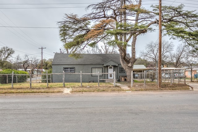 512 Ave J, Ozona, TX 76943 - view of front of home featuring a fenced front yard, stucco siding, a shingled roof, and a gate