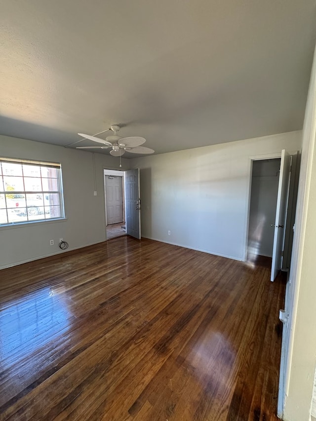 empty room with ceiling fan and dark hardwood / wood-style flooring