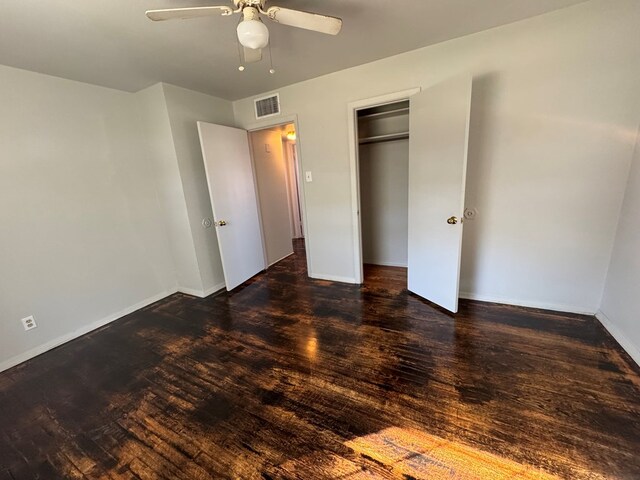 unfurnished bedroom featuring dark wood-type flooring, ceiling fan, and a closet