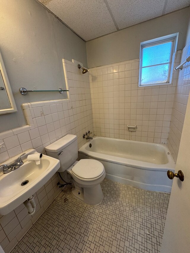 full bathroom featuring sink, tile walls, backsplash, tiled shower / bath combo, and toilet