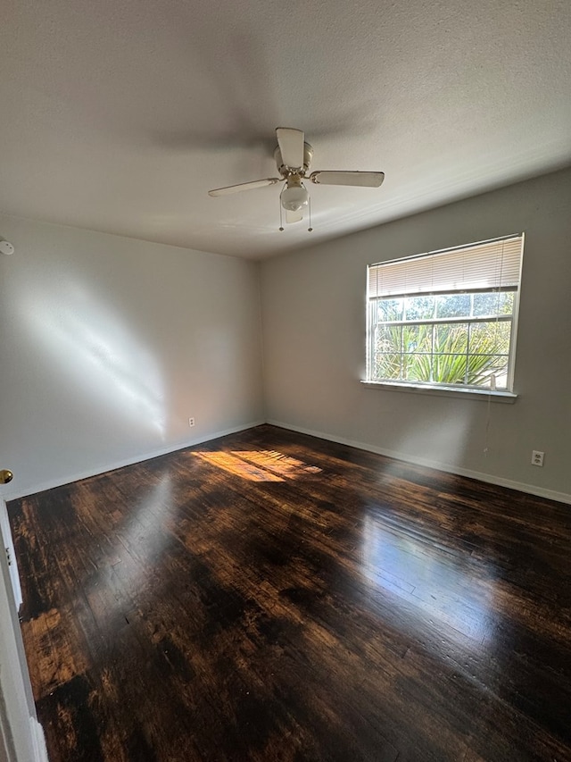 empty room featuring dark wood-type flooring and ceiling fan