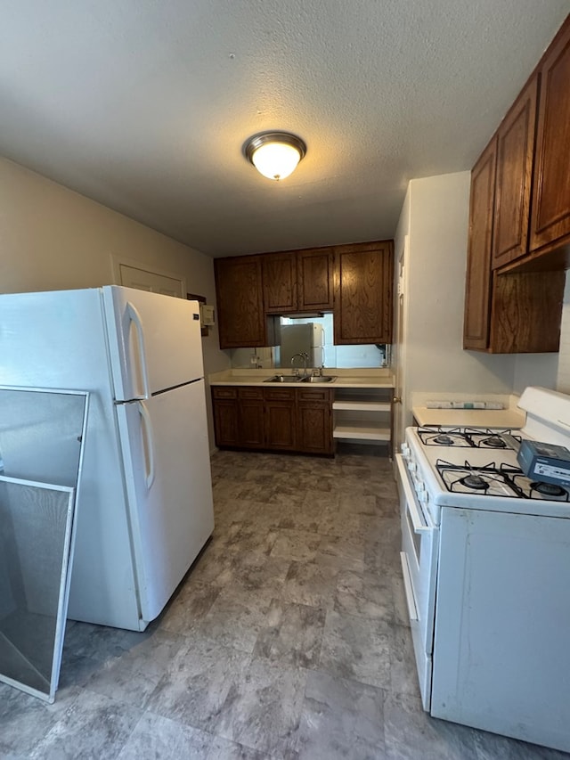 kitchen featuring white appliances, sink, and a textured ceiling