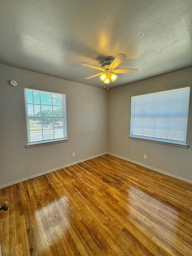 spare room with ceiling fan, plenty of natural light, a textured ceiling, and light wood-type flooring