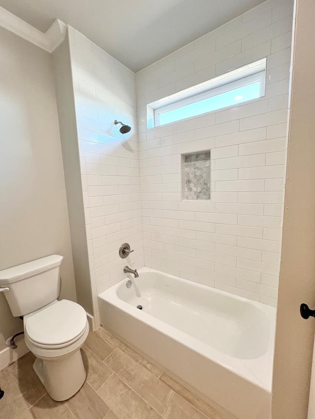 bathroom featuring ornamental molding, toilet, and tiled shower / bath combo