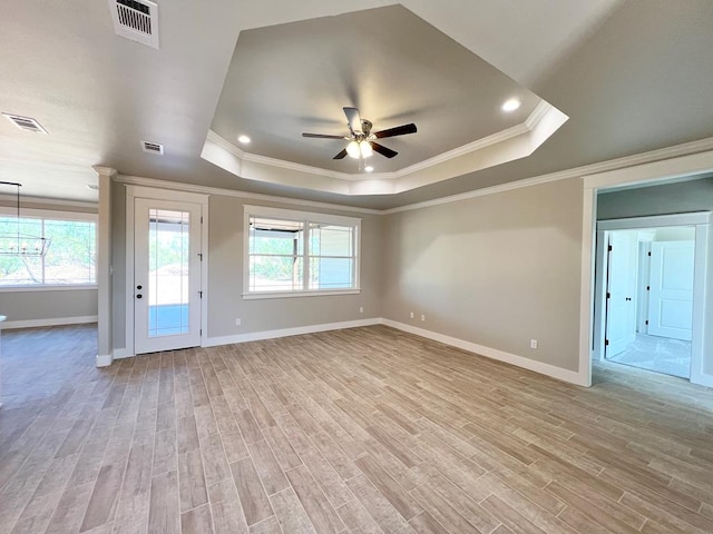 empty room featuring ornamental molding, a tray ceiling, and light hardwood / wood-style floors