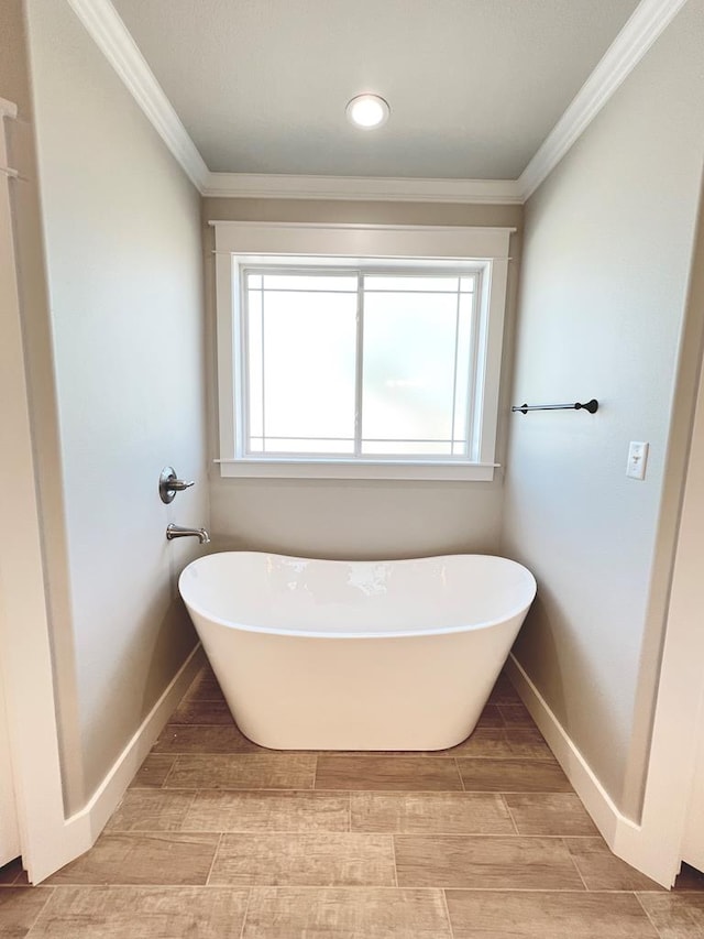 bathroom with a bathing tub, plenty of natural light, and crown molding