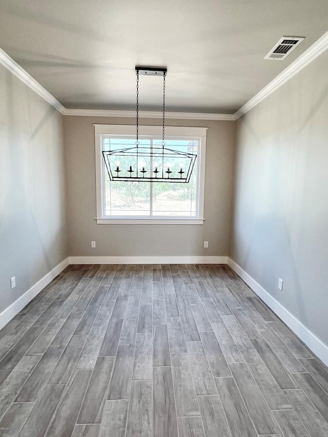 unfurnished dining area featuring crown molding, hardwood / wood-style floors, and an inviting chandelier