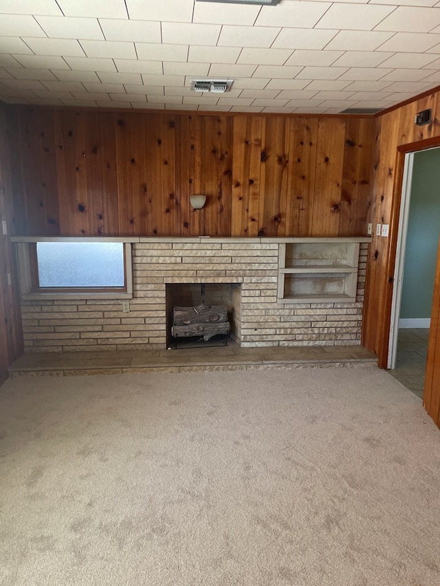 unfurnished living room featuring wooden walls and carpet