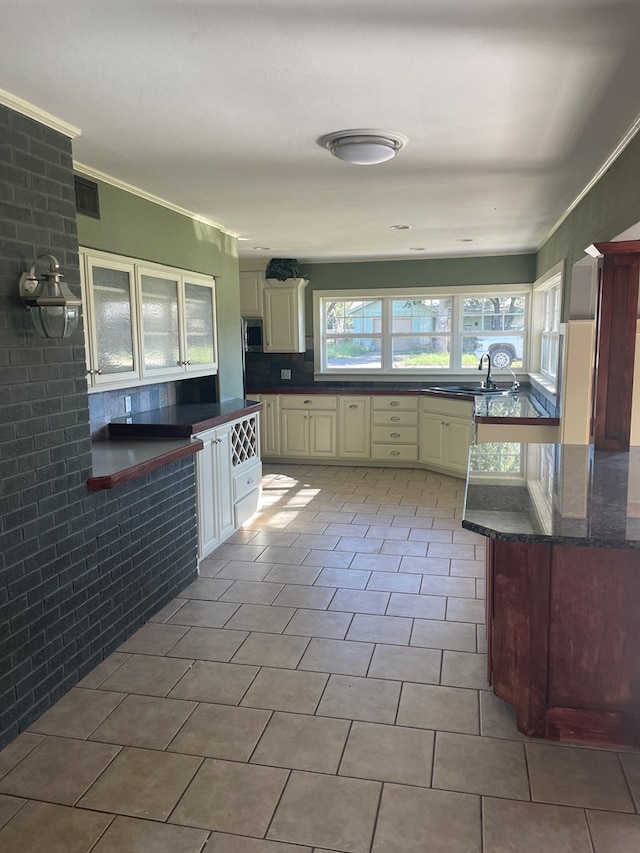 kitchen featuring sink, decorative backsplash, ornamental molding, light tile patterned floors, and cream cabinets