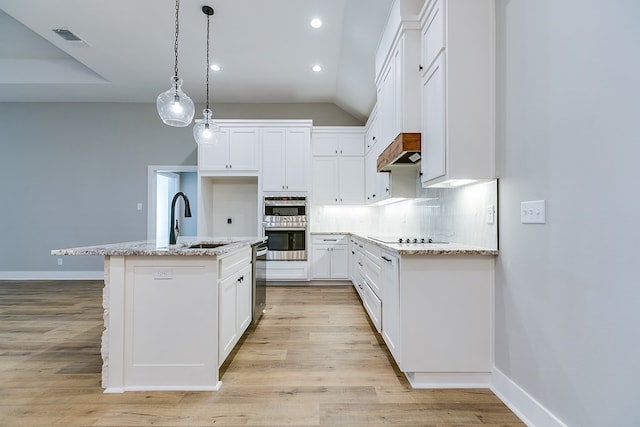 kitchen with pendant lighting, sink, a kitchen island with sink, white cabinets, and decorative backsplash