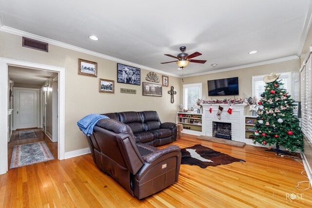 living room featuring hardwood / wood-style flooring, a wealth of natural light, ornamental molding, and ceiling fan