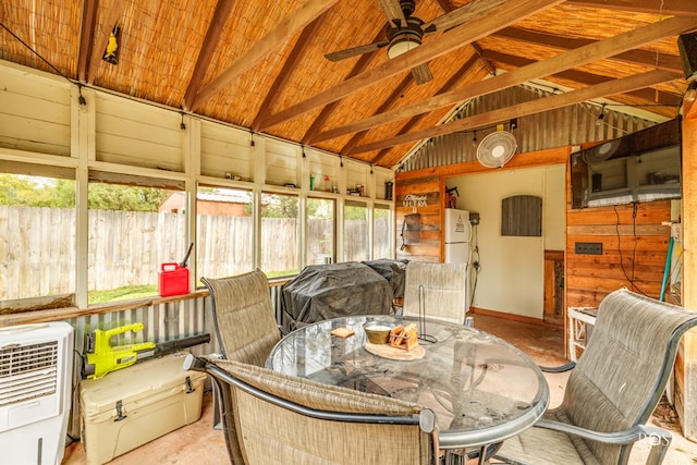 sunroom featuring ceiling fan, heating unit, and vaulted ceiling with beams