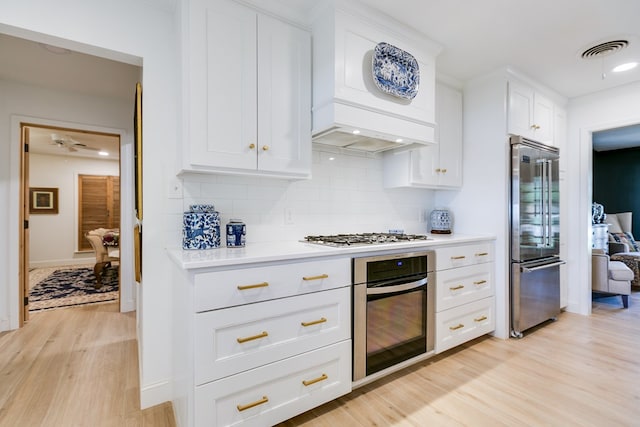2121 Sul Ross St, San Angelo, TX 76904 - kitchen featuring stainless steel appliances, light wood-style floors, backsplash, white cabinetry, and light countertops