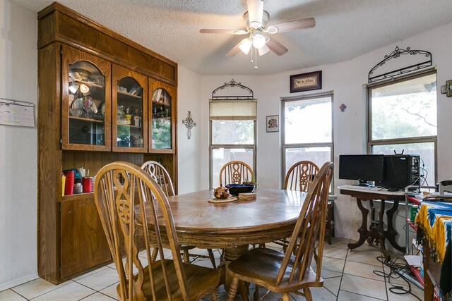 tiled dining space with ceiling fan and a textured ceiling