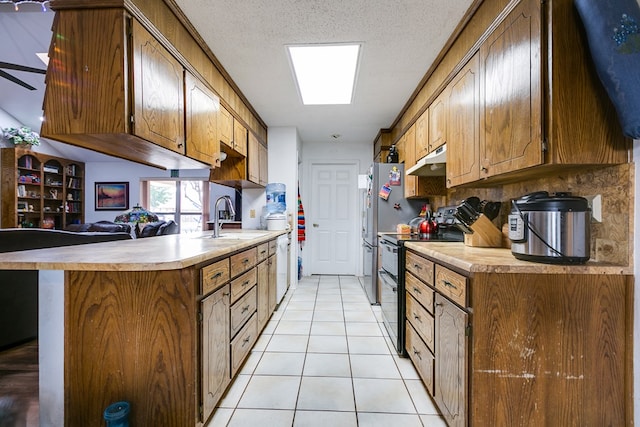 kitchen with sink, a skylight, a textured ceiling, double oven range, and kitchen peninsula