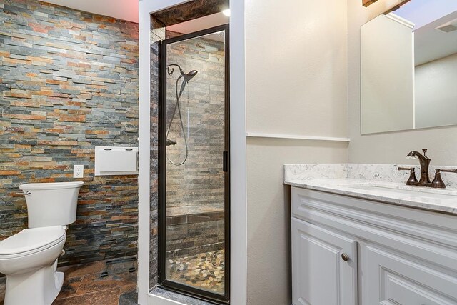 bathroom featuring a shower with door, vanity, and toilet