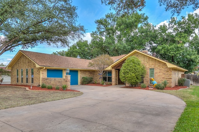 ranch-style home with a garage and central air condition unit