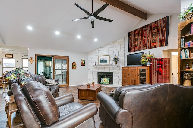 living room with a stone fireplace, high vaulted ceiling, hardwood / wood-style flooring, ceiling fan, and beam ceiling