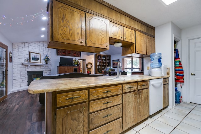 kitchen featuring sink, a fireplace, light tile patterned flooring, vaulted ceiling, and kitchen peninsula