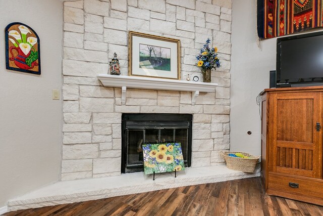 details with hardwood / wood-style flooring and a stone fireplace