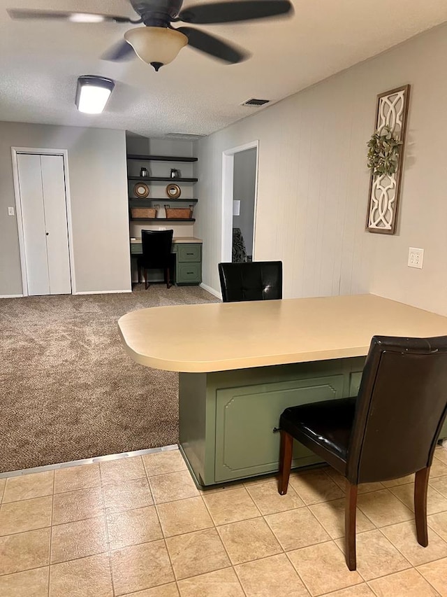 carpeted office with ceiling fan and built in desk