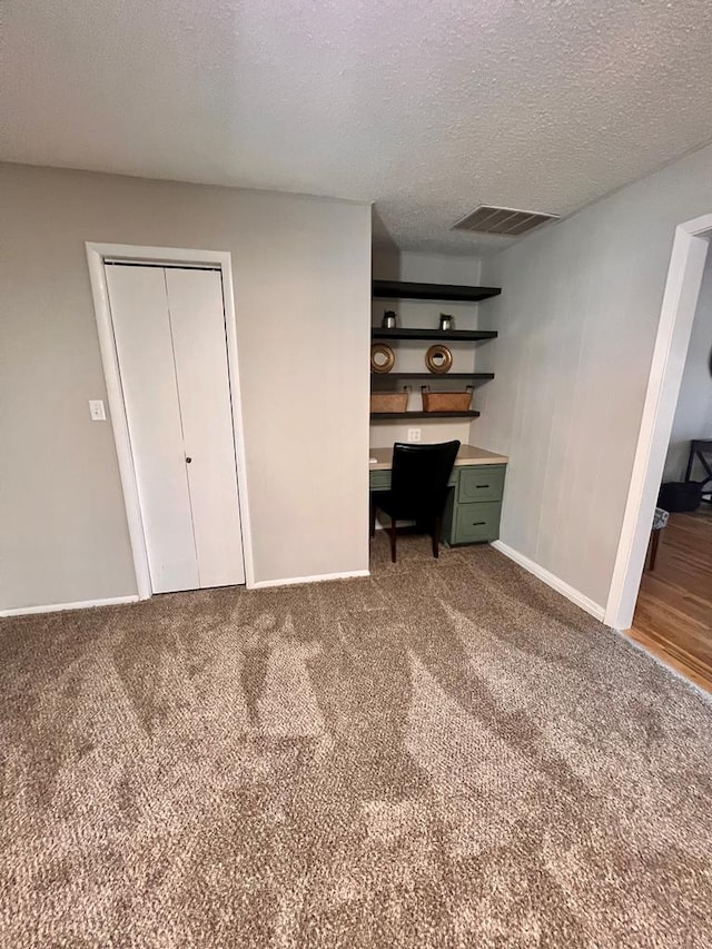 unfurnished bedroom featuring carpet, a textured ceiling, and a closet