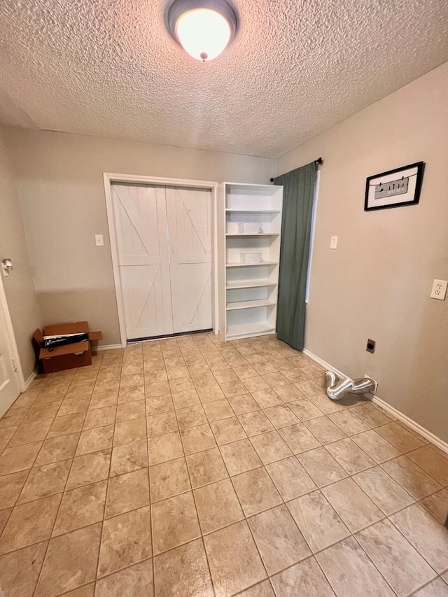 clothes washing area with light tile patterned floors, hookup for an electric dryer, and a textured ceiling