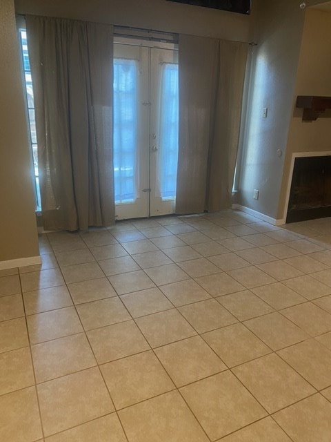 3603 Nevada Dr, San Angelo, TX 76904 - spare room featuring light tile patterned floors, french doors, and a fireplace