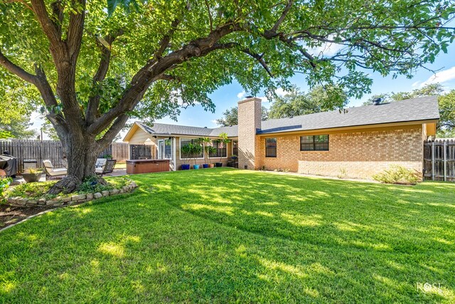 3513 Lindenwood Dr, San Angelo, TX 76904 - back of property featuring a hot tub, a chimney, a fenced backyard, brick siding, and a patio